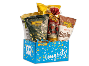 Congrats basket box, blue background with gold and white dots, pretzels on box filled with various Unique Snacks products